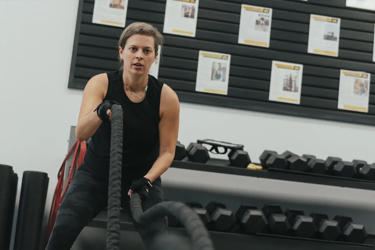A woman drives battle ropes during a strength session at the studio