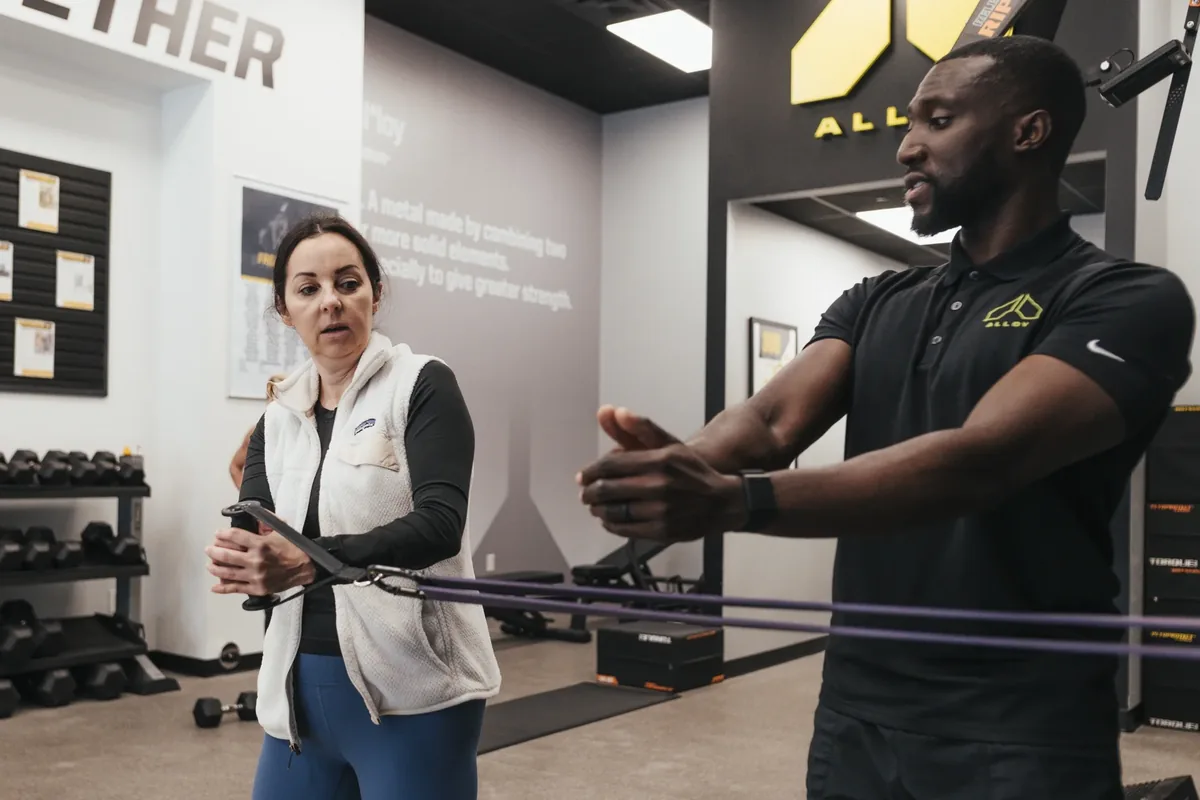 Trainer demonstrates a resistance band movement for a member at Alloy Personal Training — Billings, MT